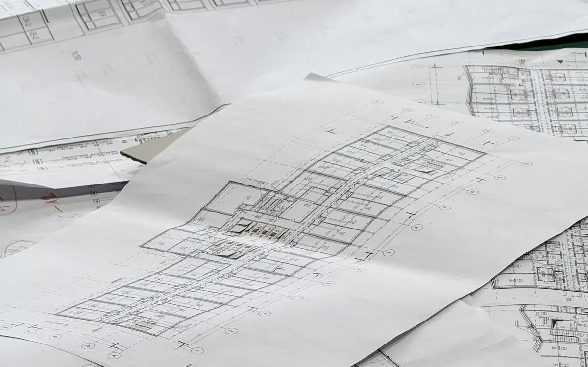 Rysunki architektoniczne rozłożone na powierzchni roboczej.