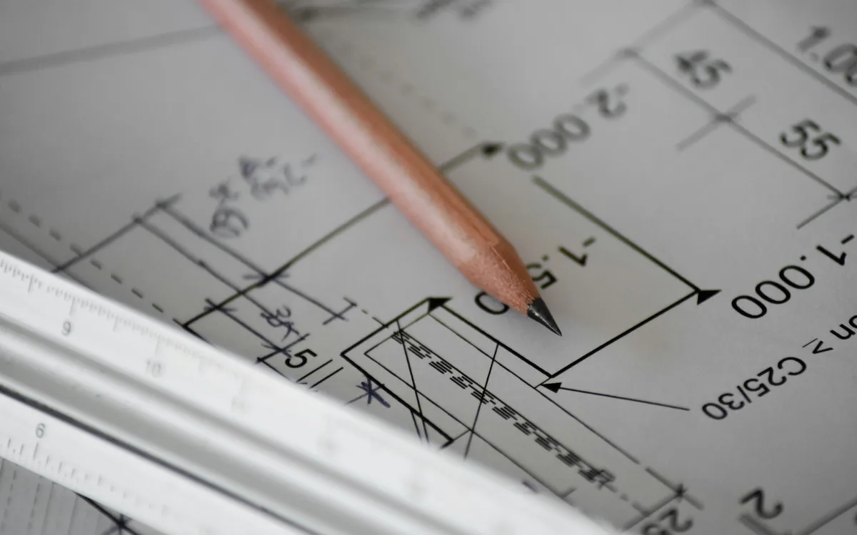Ołówek na rysunku technicznym z wymiarami i liniami projektu.